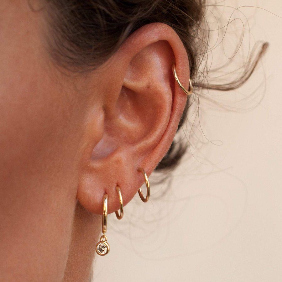 gold sleeper hoops layered with huggie hoops with solitaired diamond