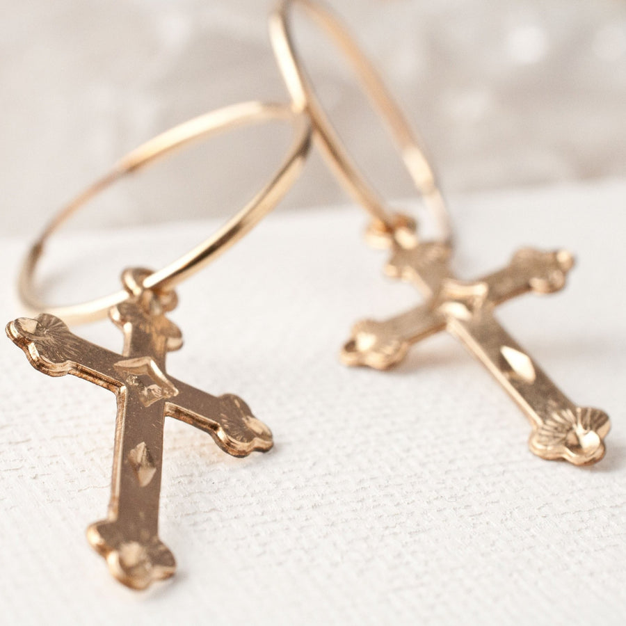 Gold hoop earrings with cross on white background