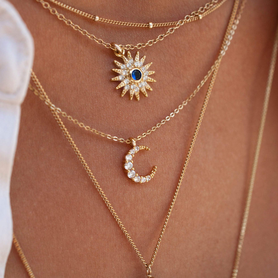 Layering gold chains with tiny crescent moon necklace and starburst necklace